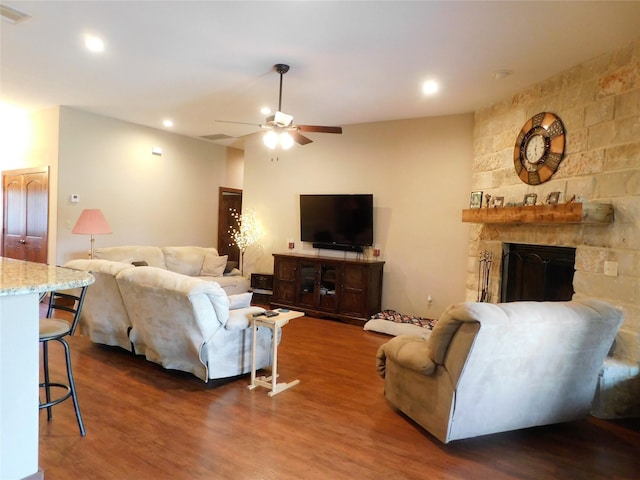 living room featuring ceiling fan, a fireplace, and dark hardwood / wood-style flooring