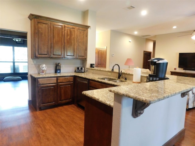 kitchen with ceiling fan, sink, kitchen peninsula, a breakfast bar, and dark hardwood / wood-style flooring