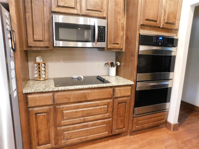 kitchen featuring light stone counters, stainless steel appliances, and light hardwood / wood-style flooring