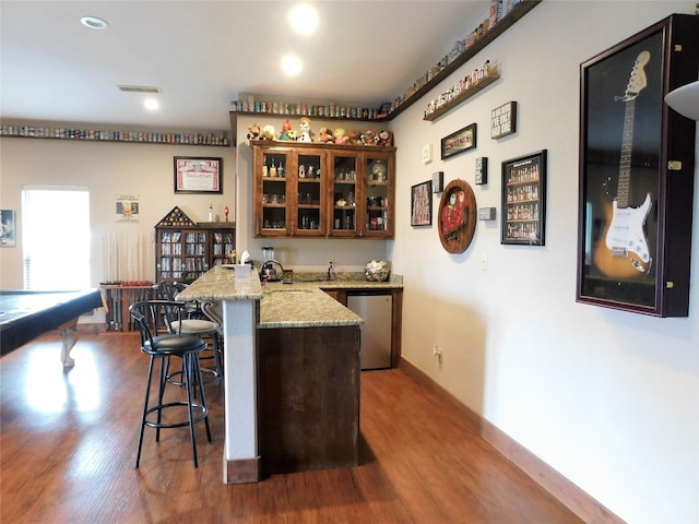 bar with dishwasher, light stone countertops, dark hardwood / wood-style floors, and sink