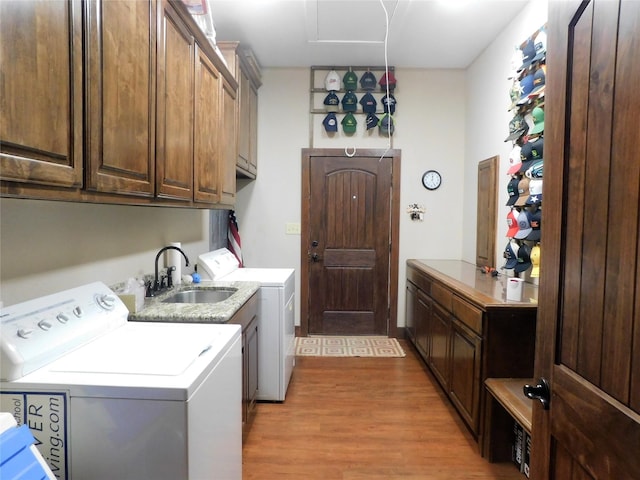 laundry area featuring cabinets, light wood-type flooring, sink, and washing machine and dryer