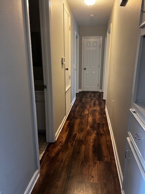 hall featuring a textured ceiling and dark wood-type flooring