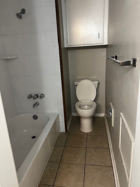 bathroom with tile patterned flooring, tiled shower / bath, and toilet