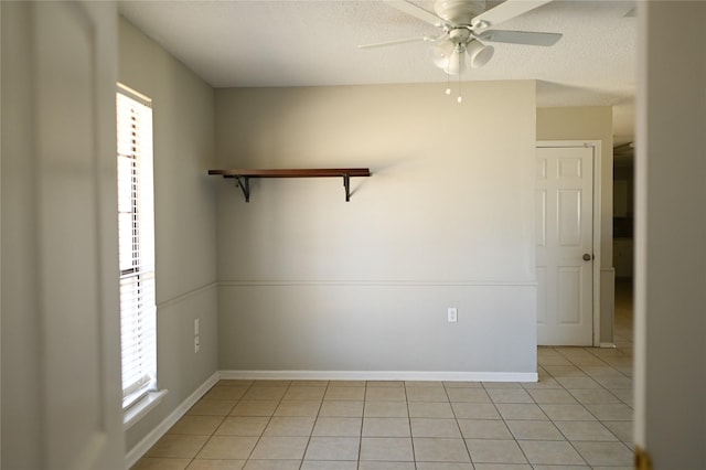 unfurnished room featuring a textured ceiling, light tile patterned flooring, a ceiling fan, and baseboards