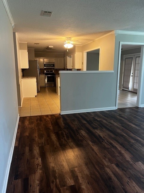 kitchen featuring ceiling fan, ornamental molding, a textured ceiling, appliances with stainless steel finishes, and light wood-type flooring