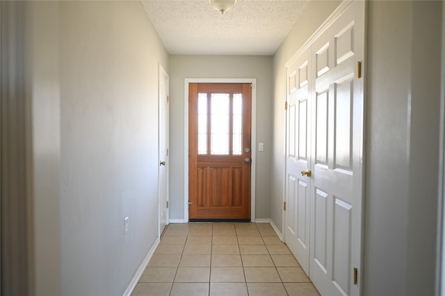 doorway to outside featuring light tile patterned floors, baseboards, and a textured ceiling