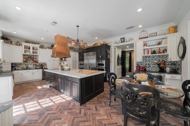 kitchen featuring crown molding, hanging light fixtures, appliances with stainless steel finishes, tasteful backsplash, and a kitchen island