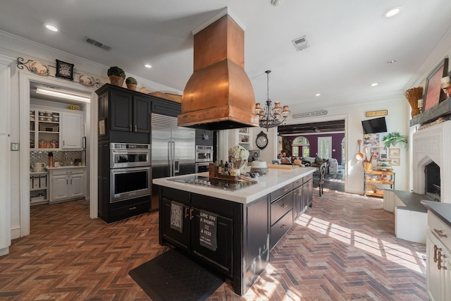 kitchen with dark parquet floors, appliances with stainless steel finishes, custom range hood, and ornamental molding