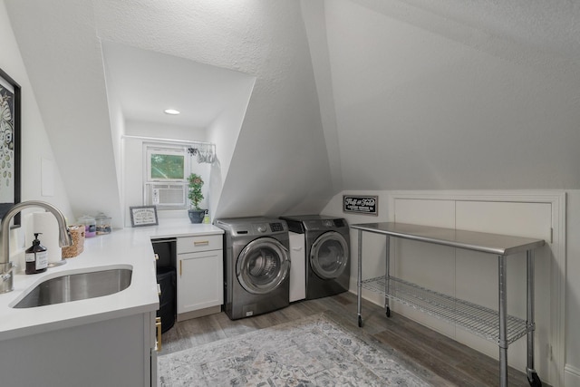 clothes washing area featuring cabinets, a textured ceiling, sink, independent washer and dryer, and light hardwood / wood-style floors