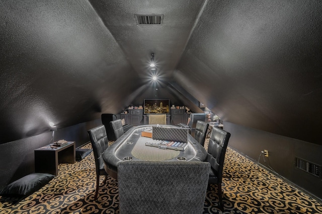 carpeted home theater room with a textured ceiling and lofted ceiling