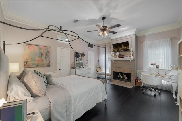 bedroom featuring ceiling fan, a fireplace, ornamental molding, and dark hardwood / wood-style flooring