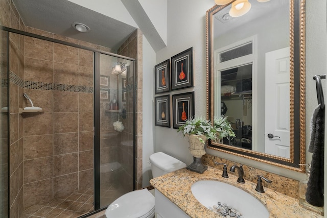 bathroom featuring toilet, an enclosed shower, a textured ceiling, and vanity