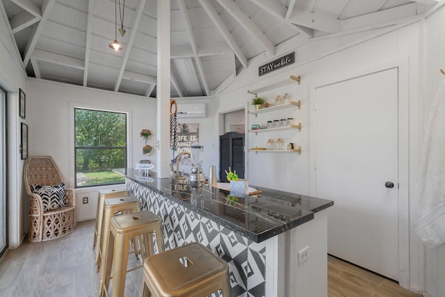 kitchen featuring light wood-type flooring, wooden ceiling, dark stone countertops, vaulted ceiling with beams, and a breakfast bar area