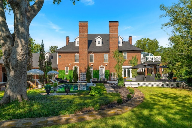 rear view of house with a swimming pool side deck and a lawn