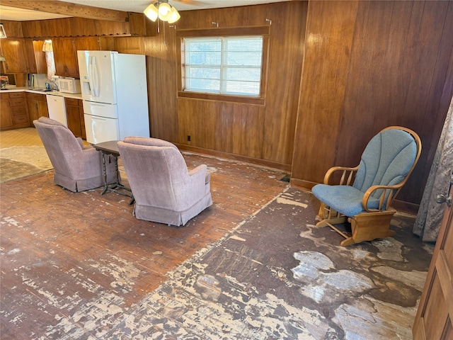 interior space with beamed ceiling, a ceiling fan, and wood walls