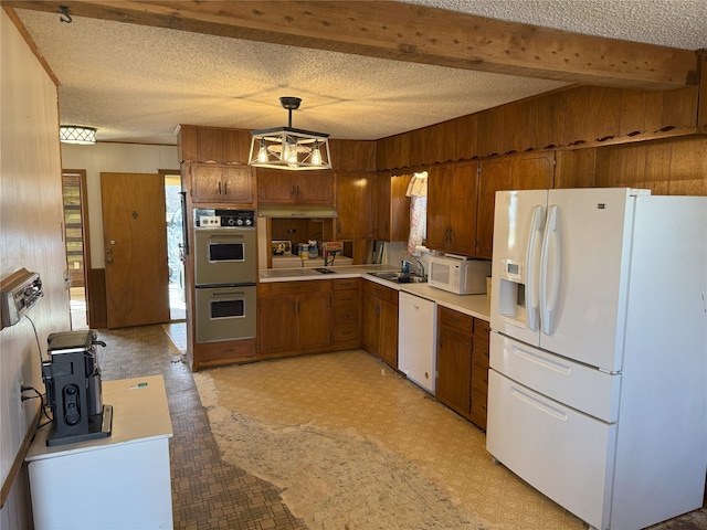 kitchen with light floors, light countertops, white appliances, a textured ceiling, and a sink