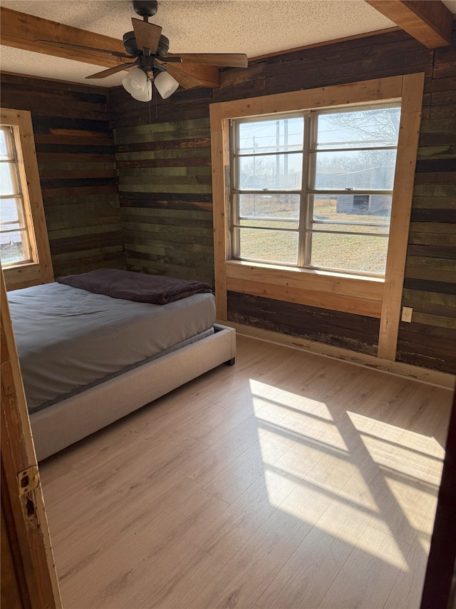 unfurnished bedroom featuring wood finished floors, beam ceiling, and wood walls