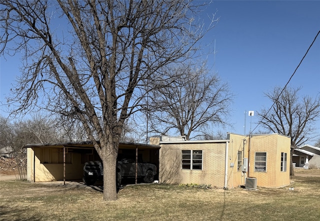 exterior space featuring a carport, a front yard, brick siding, and central AC