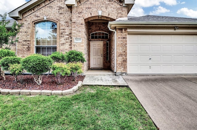 view of exterior entry with a garage and a yard