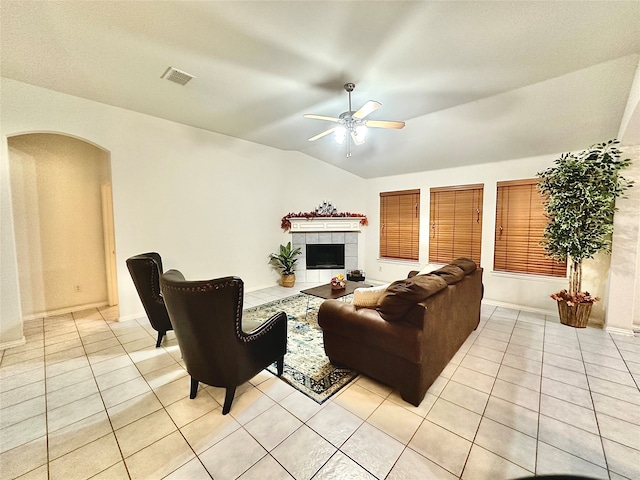 tiled living room with a fireplace, ceiling fan, and vaulted ceiling