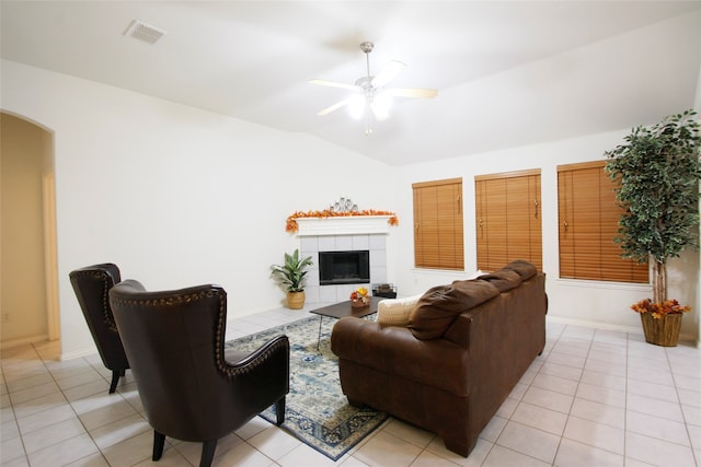 living room featuring a tiled fireplace, lofted ceiling, light tile patterned floors, and ceiling fan