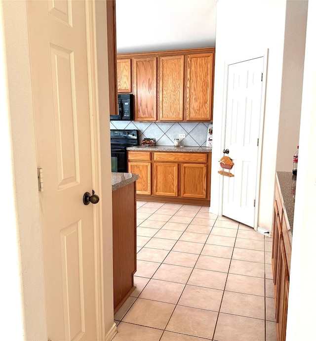 kitchen with backsplash, black appliances, and light tile patterned flooring