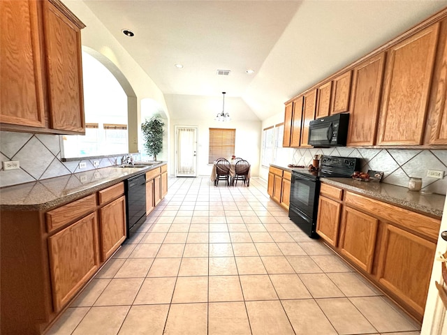 kitchen featuring lofted ceiling, sink, light tile patterned floors, pendant lighting, and black appliances