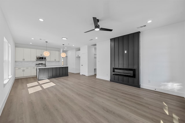 unfurnished living room featuring light hardwood / wood-style flooring and ceiling fan