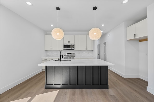 kitchen featuring white cabinets, appliances with stainless steel finishes, decorative light fixtures, and sink