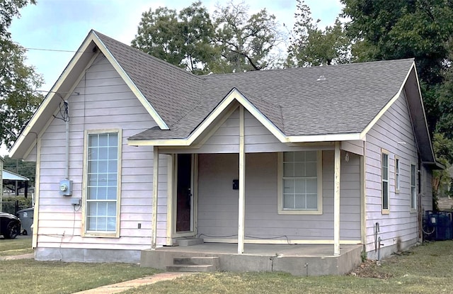 bungalow with cooling unit, a front lawn, and covered porch