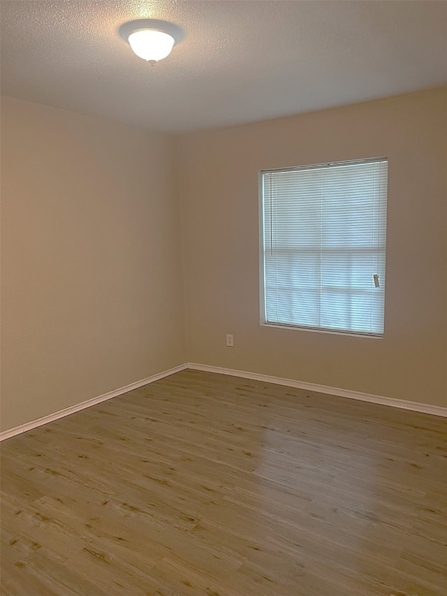 spare room featuring a textured ceiling and light hardwood / wood-style floors