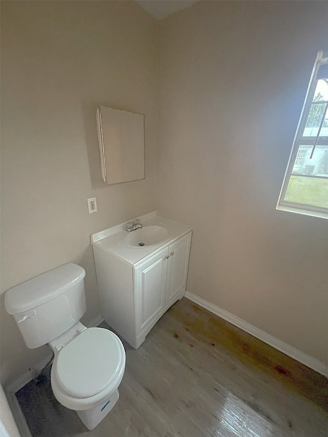 bathroom with toilet, vanity, and hardwood / wood-style floors