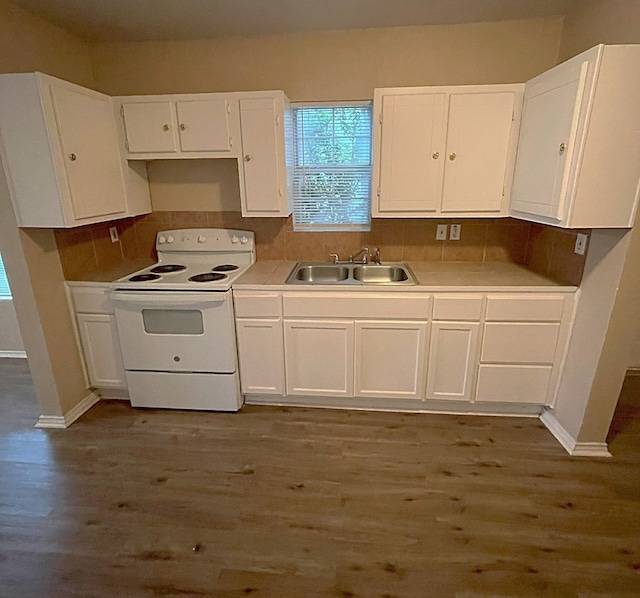 kitchen with tasteful backsplash, white cabinets, dark hardwood / wood-style flooring, white range with electric stovetop, and sink