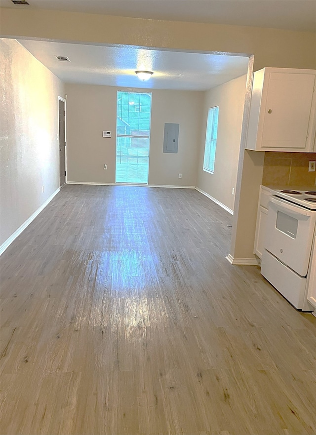 interior space with electric stove, electric panel, light wood-type flooring, and white cabinetry