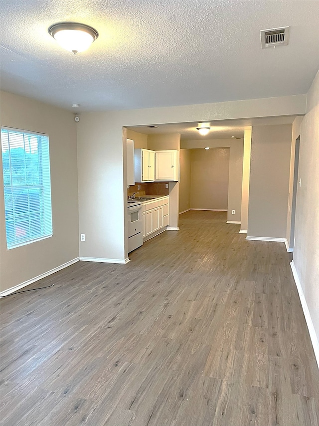 unfurnished living room featuring light wood-type flooring and a textured ceiling