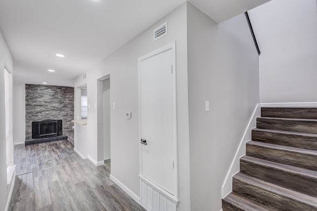 stairs with wood-type flooring and a fireplace