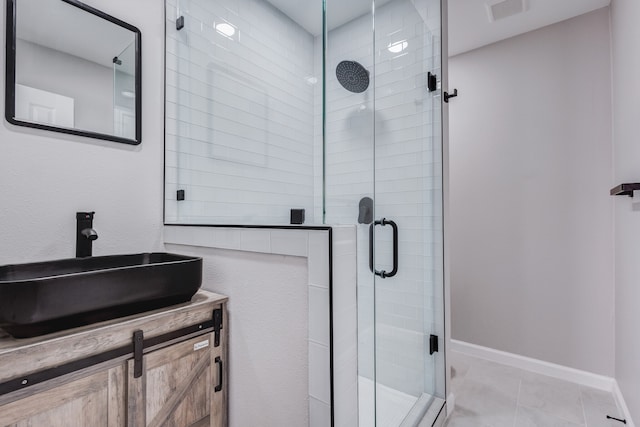 bathroom featuring tile patterned floors, a shower with door, and vanity