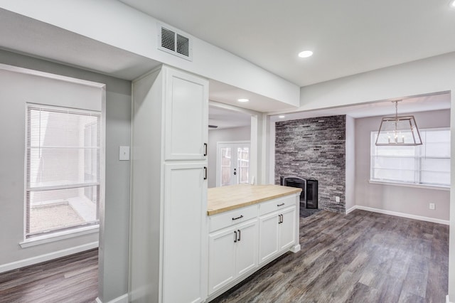 kitchen with visible vents, dark wood finished floors, white cabinets, and a fireplace
