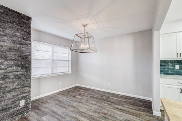 unfurnished dining area featuring dark wood-type flooring and a chandelier