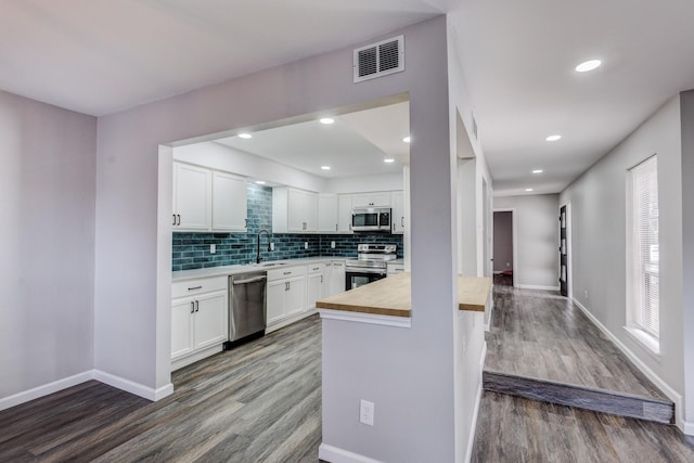 kitchen with visible vents, wooden counters, dark wood-style flooring, a sink, and appliances with stainless steel finishes