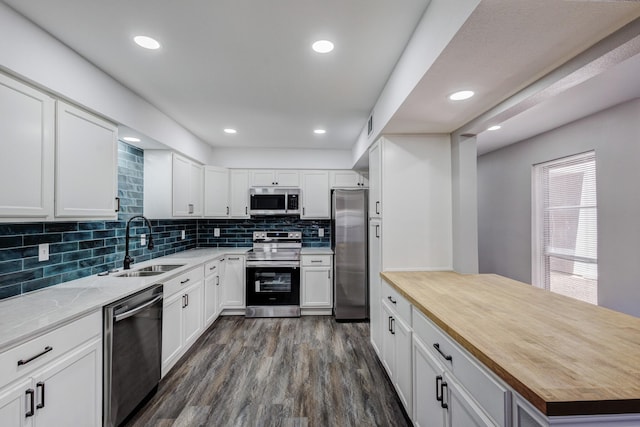 kitchen with dark wood finished floors, a sink, butcher block countertops, stainless steel appliances, and tasteful backsplash