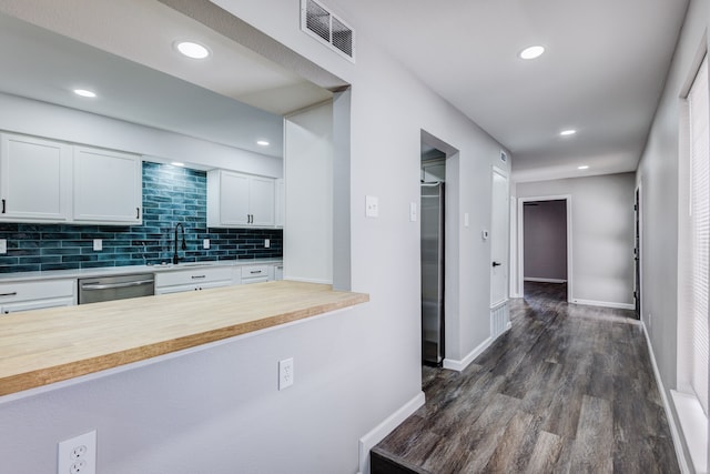 kitchen featuring dark wood-type flooring, white cabinets, butcher block counters, stainless steel appliances, and sink