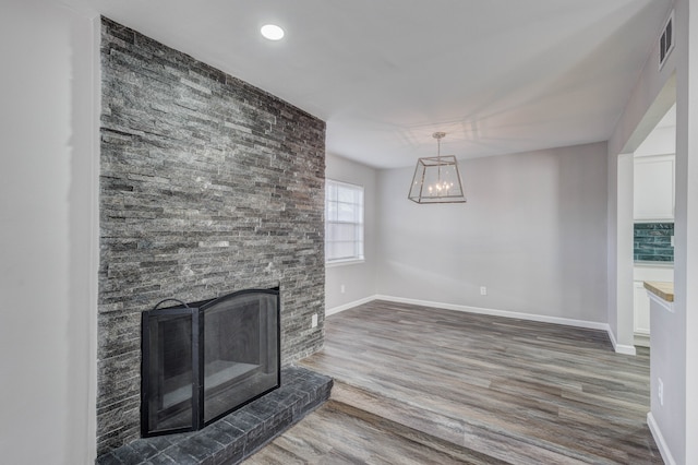 unfurnished living room with a large fireplace, a chandelier, and hardwood / wood-style floors