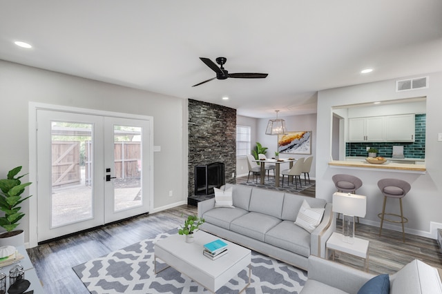 living room featuring ceiling fan, a fireplace, french doors, and dark hardwood / wood-style flooring