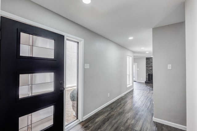 foyer entrance featuring a stone fireplace, dark hardwood / wood-style floors, and a wealth of natural light