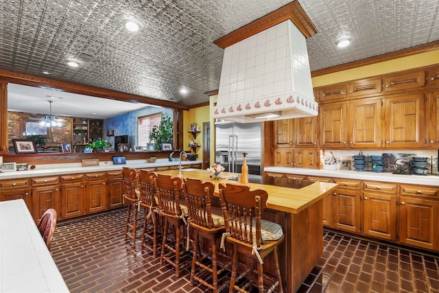 kitchen with stainless steel built in fridge, pendant lighting, ornamental molding, and wood counters