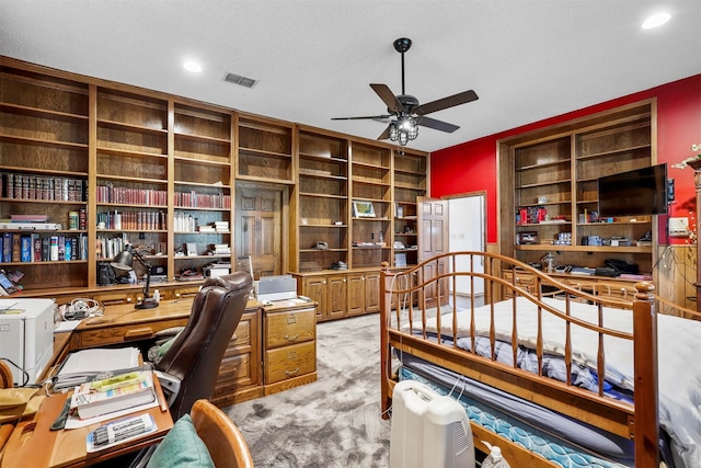 carpeted office with a textured ceiling and ceiling fan