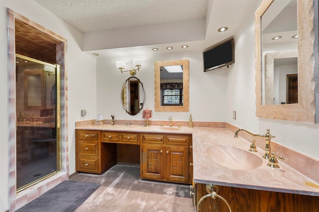 bathroom featuring a textured ceiling, vanity, and a shower with door