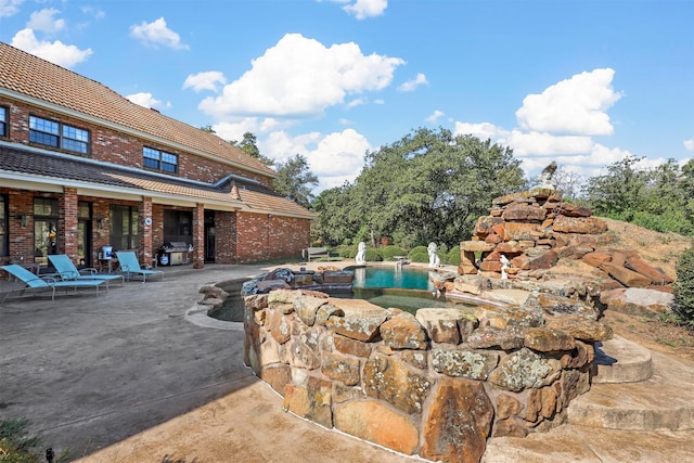 view of pool featuring area for grilling and a patio