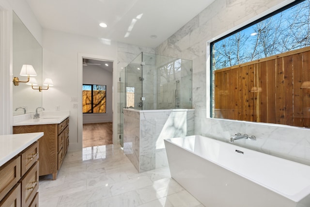 bathroom featuring marble finish floor, a healthy amount of sunlight, a shower stall, and vanity